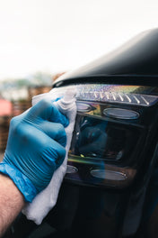 Headlight being cleaned with ceramic glass cleaner and getting wiped away